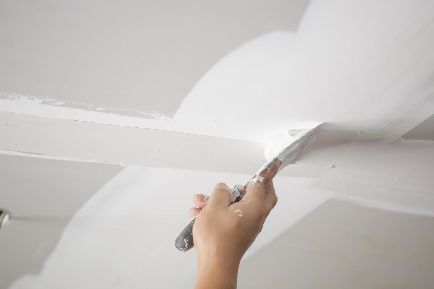 someone using a nail gun to nail roofing shingles